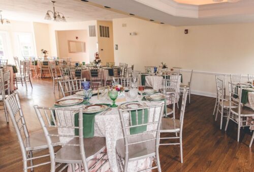 Indoor reception hall with round tables, green runners and Chiavari chairs at a Dayton and Cincinnati area wedding venue