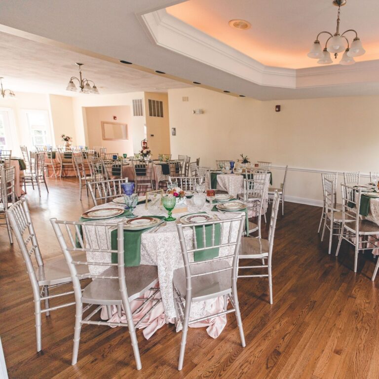 Indoor reception hall with round tables, green runners and Chiavari chairs at a Dayton and Cincinnati area wedding venue