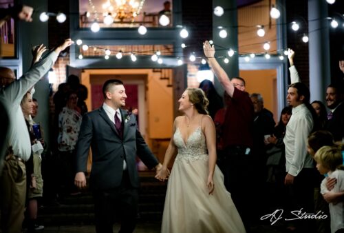 Newlyweds celebrating their grand entrance under string lights as guests cheer
