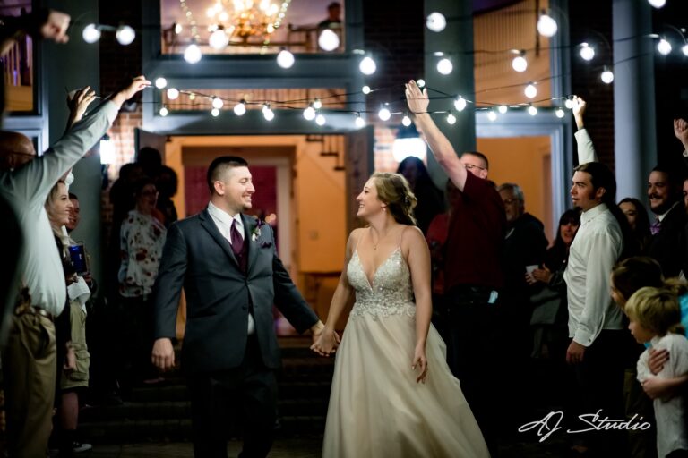 Newlyweds celebrating their grand entrance under string lights as guests cheer