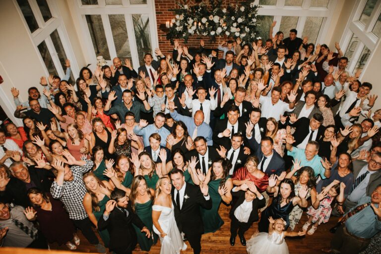 Large group of wedding guests posing together in the reception hall at The Estate at Sunset Farm